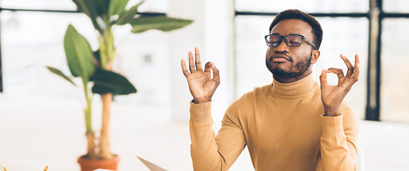 Ein Mann mit Brille meditiert und entspannt im Büro